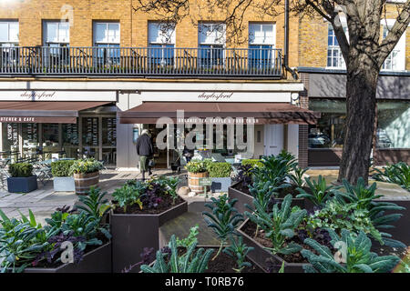 Une femme avec son chien à l'extérieur de Daylesford Organic Food shop sur Pimlico Road, Belgravia, Londres SW1 Banque D'Images