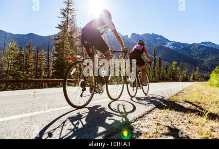 Un jeune couple riding leur vélo jusqu'au col de Washington North Cascades de l'État de Washington, USA. Banque D'Images