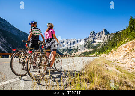 Un jeune couple debout avec leurs bicyclettes en attente d'autres cavaliers. Col de Washington dans le Nord des cascades de l'État de Washington, USA. Banque D'Images