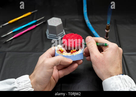 Technicien dentaire ou un dentiste avec un homme travaillant dans un laboratoire de prothèses avec de la cire sur un modèle de la mâchoire Banque D'Images