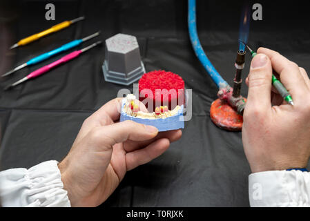 Technicien dentaire ou un dentiste avec un homme travaillant dans un laboratoire de prothèses avec de la cire sur un modèle de la mâchoire Banque D'Images