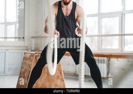 Fit man working out avec bataille au hall des cordes. L'entraînement des athlètes masculins avec des cordes en club de remise en forme Banque D'Images