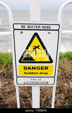 Un panneau d'avertissement pour 'Sudden Drop' situé au parc Cliffe, Roker, Sunderland Banque D'Images