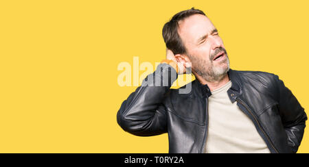 L'âge moyen bel homme vêtu de noir veste en cuir la souffrance des blessures au cou, du cou maux de toucher avec la main, des douleurs musculaires Banque D'Images