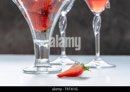 Deux tranches de fraises sur la table, le verre avec des fraises et un couple de lunettes avec verre Banque D'Images