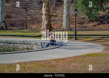 Deux jeunes filles sont assises sur le bord de l'étang dans le parc. Brooklyn, NY, Printemps 2019 Banque D'Images