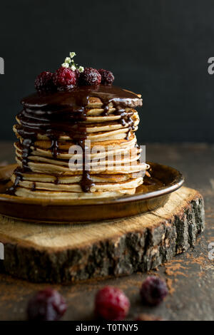 Pile de pancakes à la banane surmonté d'un filet de chocolat et de framboises surgelées Banque D'Images