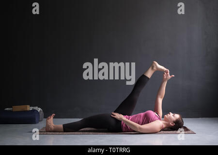 Woman doing Yoga asana Supta padangusthasana ou inclinable part à la posture du gros orteil Banque D'Images