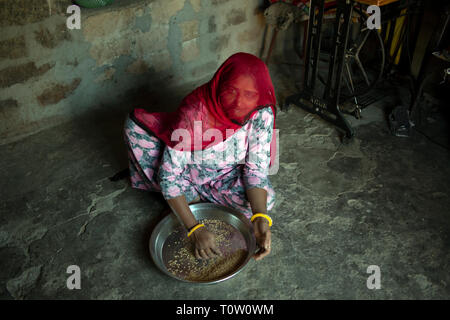 Une femme musulmane portant un voile prépare millet dans sa maison. Village de Kakani, Jodhpur, Rajasthan, Inde. Banque D'Images