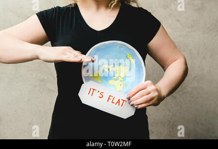 Télévision Earther concept. Personne qui croit que la terre est un disque plat. Woman holding anonyme modèle de terre plate à l'avant de son corps avec du texte : il est plat. La norme iso Banque D'Images