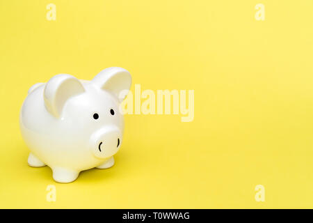 White piggy-bank sur fond jaune, copiez-space Banque D'Images