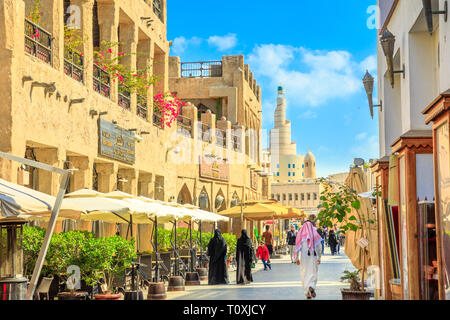 Doha, Qatar - 20 Février 2019 : les femmes et les hommes en vêtements traditionnels arabes à pied le long de la rue Main à l'intérieur de Souq Waqif vieux marché avec cafés et restaur Banque D'Images