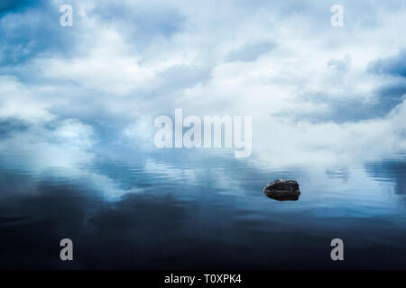 Paysage du lac à l'horizon au-dessus de l'eau avec le brouillard et les nuages reflètent et un rock sombre solitude Banque D'Images