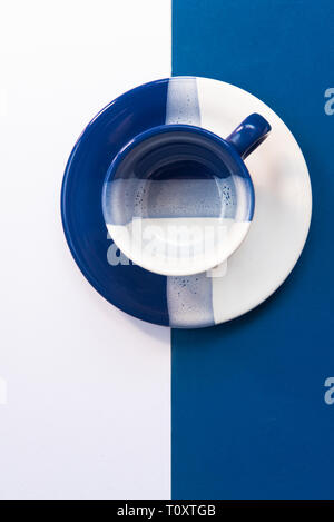 Blanc et bleu tasse à café vide reposant sur un fond blanc et bleu Banque D'Images