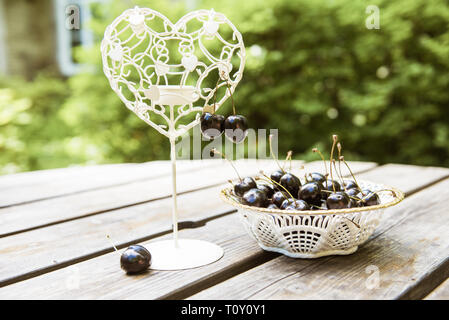 Cerises noires baies dans une assiette blanche sur la table en bois Banque D'Images