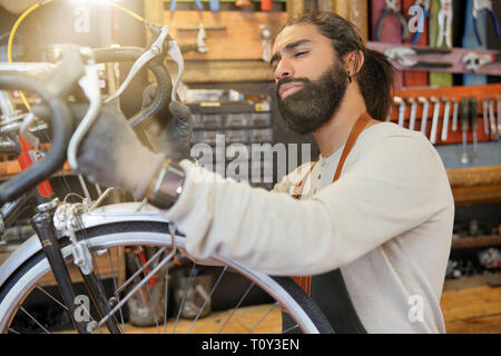 L'homme travaillant en atelier de réparation de vélo Banque D'Images