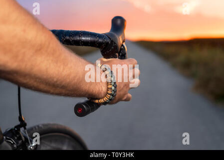 Cycliste équitation un vélo au coucher du soleil, pov vue . Banque D'Images