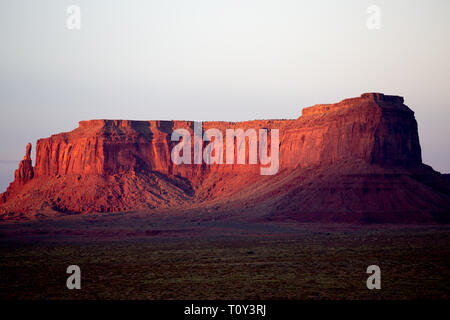 Une butte de grès rouge allumé par le coucher du soleil près de Monument Valley Village de tipis, Oljato-Monument Valley, San Juan County, Utah, l'Amérique Banque D'Images