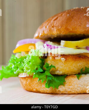 Hamburger grillé savoureux avec des nuggets de poulet, fromage, laitue, oignons, concombres Banque D'Images