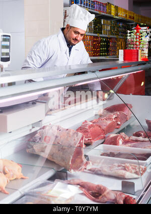 L'homme en robe blanche vendeur proposant de la viande halal au comptoir à market Banque D'Images