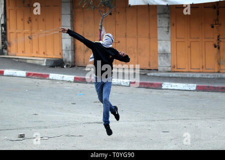 Hébron, en Cisjordanie, en territoire palestinien. Mar 22, 2019. Un manifestant palestinien jette une pierre vers les forces de sécurité israéliennes au cours d'affrontements dans la ville de Cisjordanie d'Hébron, le 22 mars 2019 Credit : Hashlamoun Wisam APA/Images/ZUMA/Alamy Fil Live News Banque D'Images