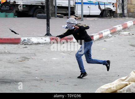 Hébron, en Cisjordanie, en territoire palestinien. Mar 22, 2019. Un manifestant palestinien jette une pierre vers les forces de sécurité israéliennes au cours d'affrontements dans la ville de Cisjordanie d'Hébron, le 22 mars 2019 Credit : Hashlamoun Wisam APA/Images/ZUMA/Alamy Fil Live News Banque D'Images