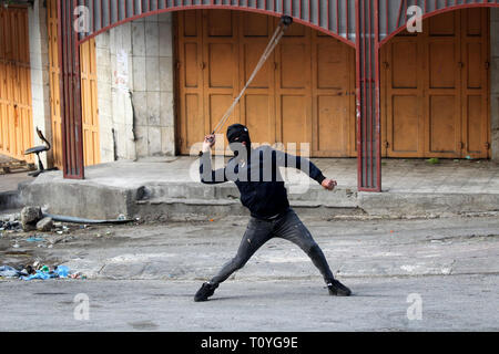 Hébron, en Cisjordanie, en territoire palestinien. Mar 22, 2019. Un manifestant palestinien jette une pierre vers les forces de sécurité israéliennes au cours d'affrontements dans la ville de Cisjordanie d'Hébron, le 22 mars 2019 Credit : Hashlamoun Wisam APA/Images/ZUMA/Alamy Fil Live News Banque D'Images