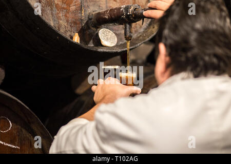 Malaga, Espagne - 2 mars, 2019 : Serveur puoring Malaga doux vin de canon. Ancienne taverne à vins traditionnels. Banque D'Images