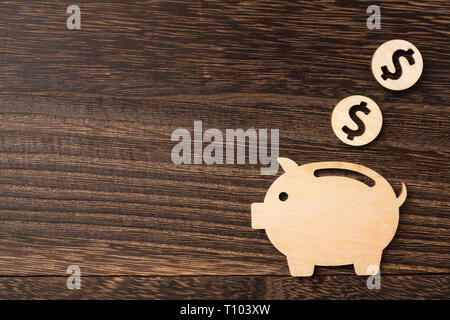 Concept design et financiers - tirelire cochon en bois pièce sur fond de bois sombre. Il s'agit d'épargne, l'investissement concept Banque D'Images