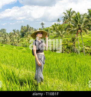 À la mode décontractée caucasian woman wearing petit sac à dos et chapeau de riz asiatique traditionnelle balade parmi de beaux champs de riz vert et Banque D'Images