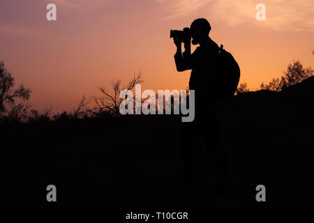 Un beardedphotographer silhouette prendre photo de coucher du soleil la lumière.. Un photographe photo pousses tard dans la soirée Banque D'Images