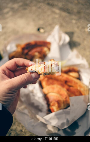 L'homme est titulaire d'un morceau de burek avec du fromage à la main, avec reste de burek floues en arrière-plan sur papier blanc Banque D'Images