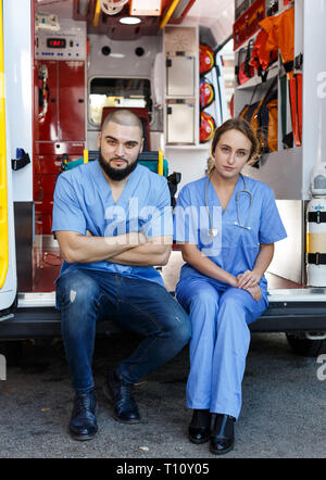 Portrait de deux ambulanciers positif assis en voiture ambulance Banque D'Images