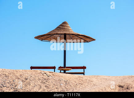 Seul soleil parasol et coin banc contre un ciel bleu. Banque D'Images