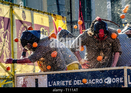 Faits saillants de la bataille de l'Orange, à Ivrea, près de Turin, en Italie, où les flammes orange sur le terrain l'attaque aux lanceurs d'orange qui defende eux-mêmes sur le chariot, et des courses d'orange Banque D'Images