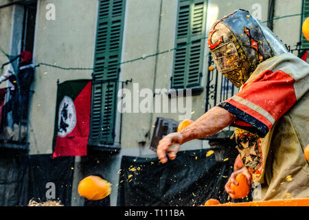 Faits saillants de la bataille de l'Orange, à Ivrea, près de Turin, en Italie, où les flammes orange sur le terrain l'attaque aux lanceurs d'orange qui defende eux-mêmes sur le chariot, et des courses d'orange Banque D'Images