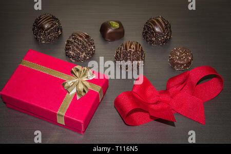 Le velours rouge présent fort avec du chocolat et de l'attaché rouge bow cadeau d'anniversaire. Banque D'Images