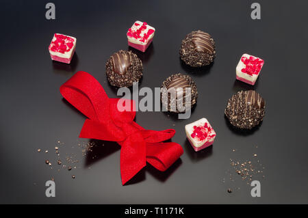 Pralines au chocolat décoré de bonbones rouge et rouge bow liée. Cadeau Anniversaire Mariage engagement événement Célébration de Pâques et l'arrière-plan. concept Banque D'Images