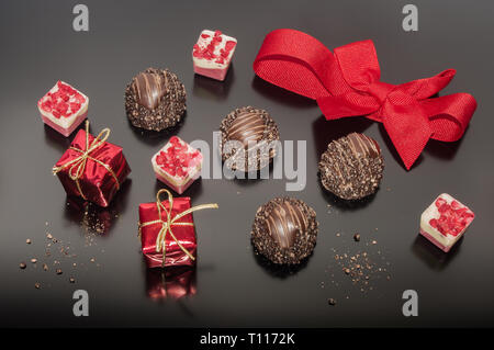 Truffes Pralines en chocolat et bonbons sur fond noir. Petite boîte carrée, cadeau, décoration avec red bow Banque D'Images