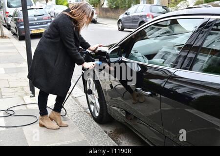 Femme de brancher sur jaguar électrique résidentielle Banque D'Images