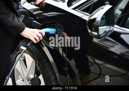 Femme de brancher sur jaguar électrique résidentielle Banque D'Images