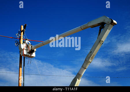 L'homme travailleur de travail sur lignes électriques dans la benne grue élevée dans l'air un travail dangereux Banque D'Images