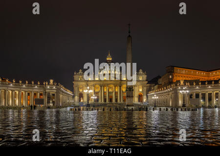 La Basilique St Pierre du cœur de la Cité du Vatican. Une chaussée mouillée reflète les lumières de l'église et de Bernini columnade Banque D'Images