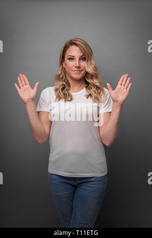 Jeune femme pose ses mains montrant la surprise ou le déni. Banque D'Images