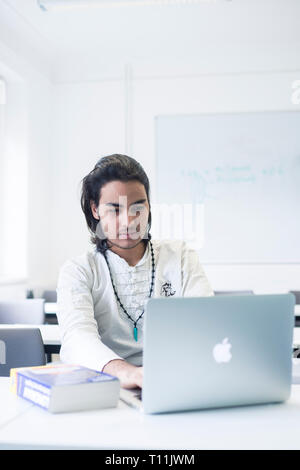 Un étudiant arabe est assis dans une salle de classe de travailler sur son ordinateur portable Banque D'Images