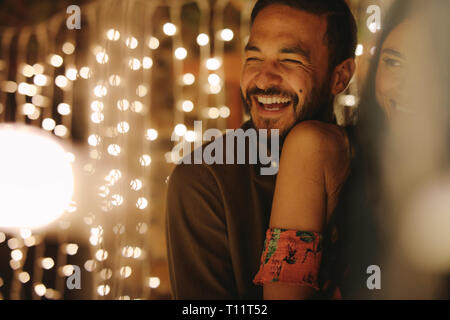 Cheerful young man embracing son amie par derrière lors d'une fête. Couple romantique à partie. Banque D'Images