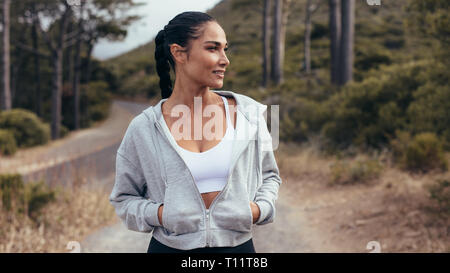 Comité permanent de l'athlète féminine à l'extérieur au cours de sa formation de remise en forme le matin. Femme en fitness wear debout sur une route vide le matin. Banque D'Images