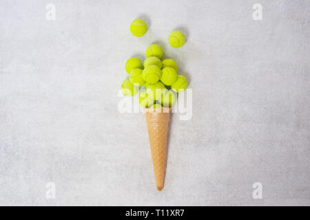 Cornet de crème glacée avec balle de tennis sur fond blanc. Concept alimentaire minimal Banque D'Images