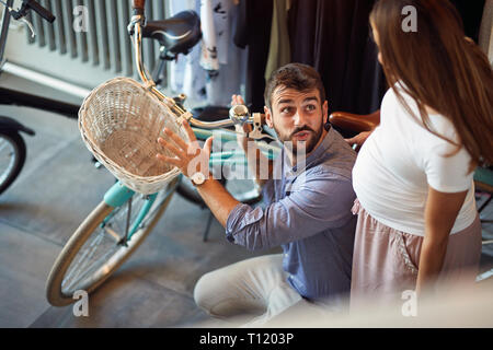 Vendeur aider femme enceinte à l'achat de nouveaux location dans bike shop Banque D'Images