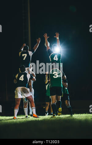 joueurs de rugby sautant pour la ligne au stade. Équipes sautant pour la possession du ballon pendant le match de rugby. Banque D'Images